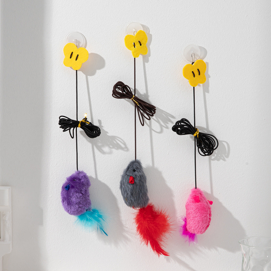 Gray, pink, and purple hanging mouse cat toys mounted on a wall