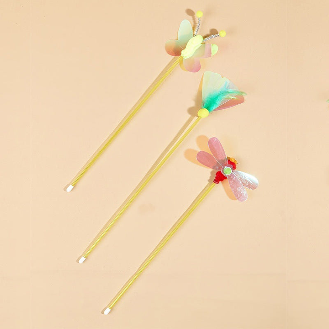 Three multicolor insect-topped cat toy wands on a peach background