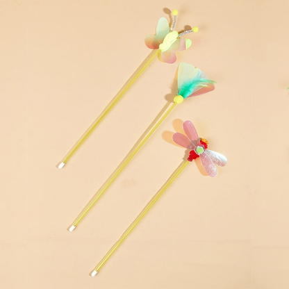 Three multicolor insect-topped cat toy wands on a peach background