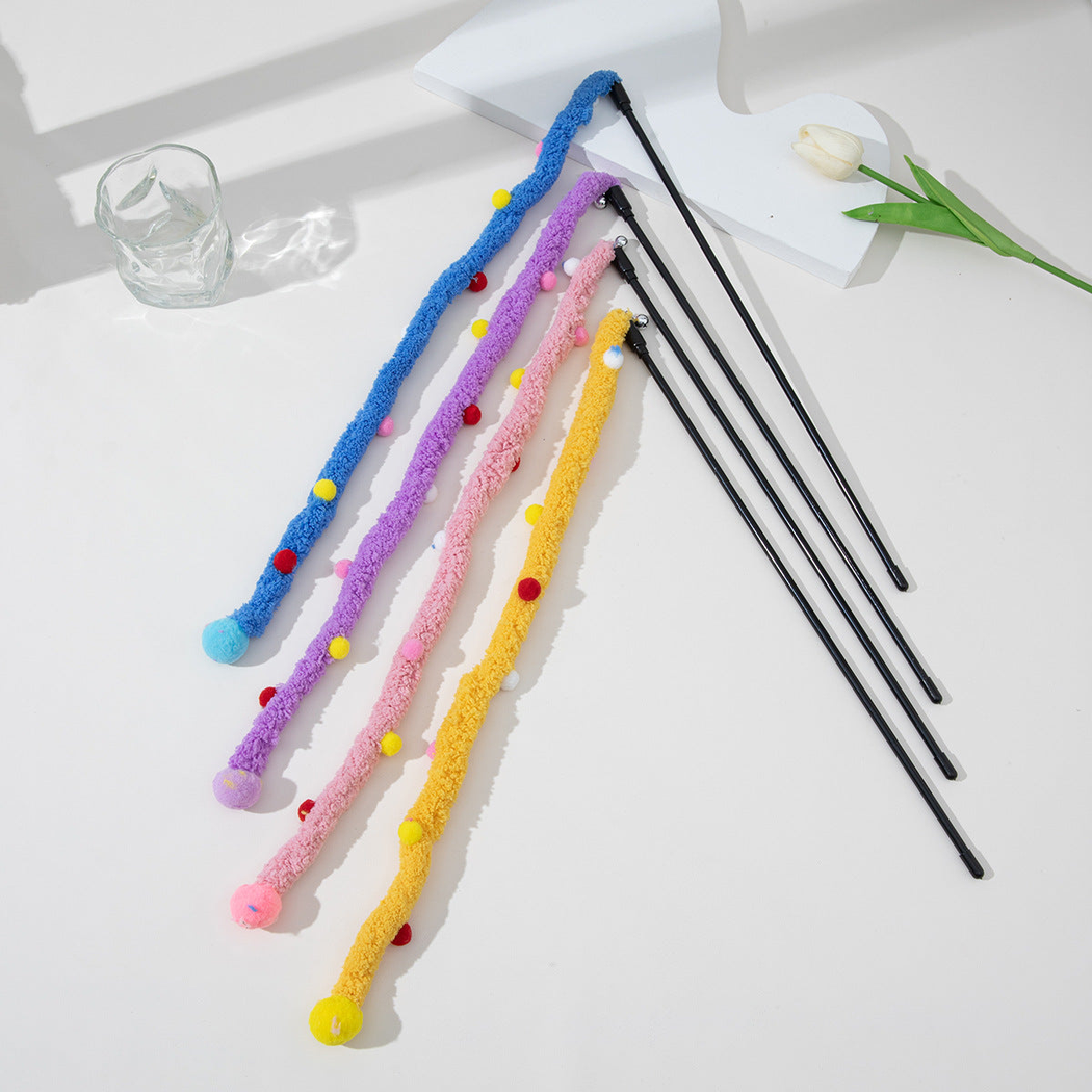 Blue, purple, pink and yellow fuzzy cat teaser wands arranged on a white tabletop