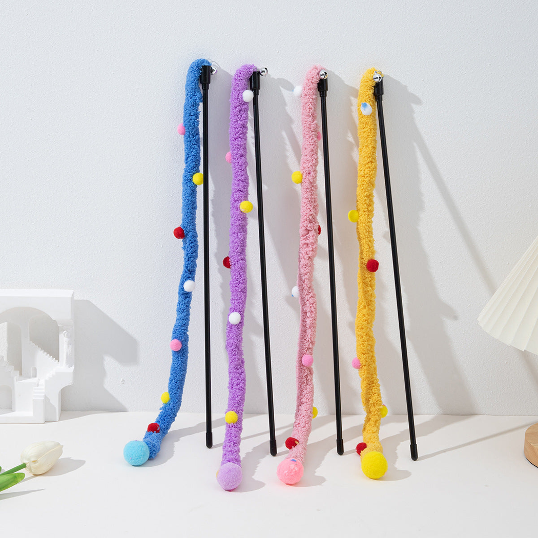 Four fuzzy cat teaser wands standing against a white wall