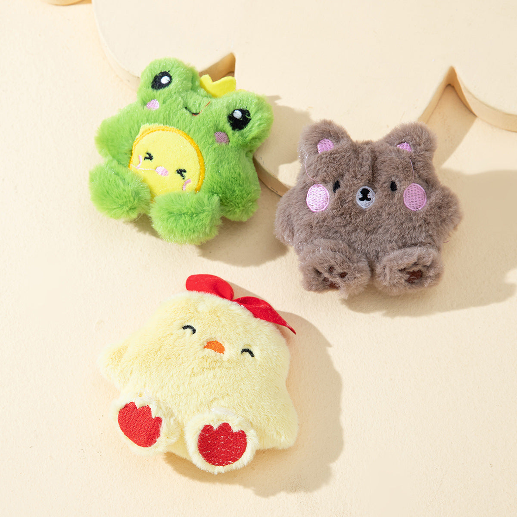 Frog, bear and yellow chick plush cat toys arranged on a cream backdrop