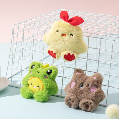 Yellow chick, green frog and brown bear plush cat toys arranged on a wire display