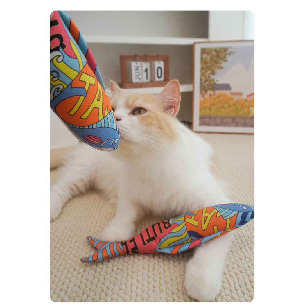 Cat beside two multicolor fish-shaped cat toys indoors