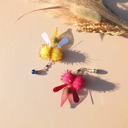 Yellow and fuchsia winged cat toy attachments displayed with their clips and bells