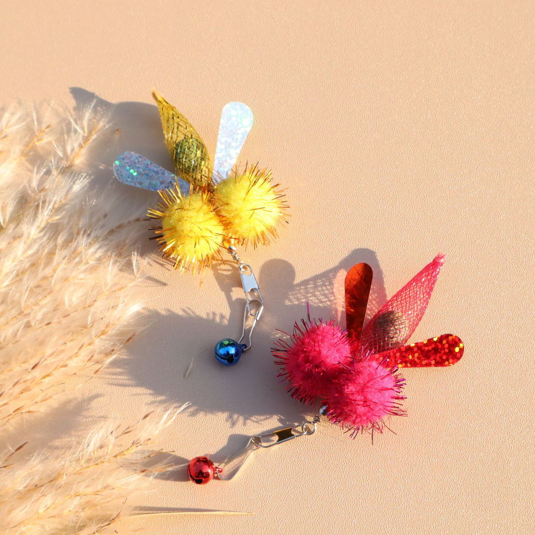 Yellow and fuchsia winged cat toy attachments on a peach background