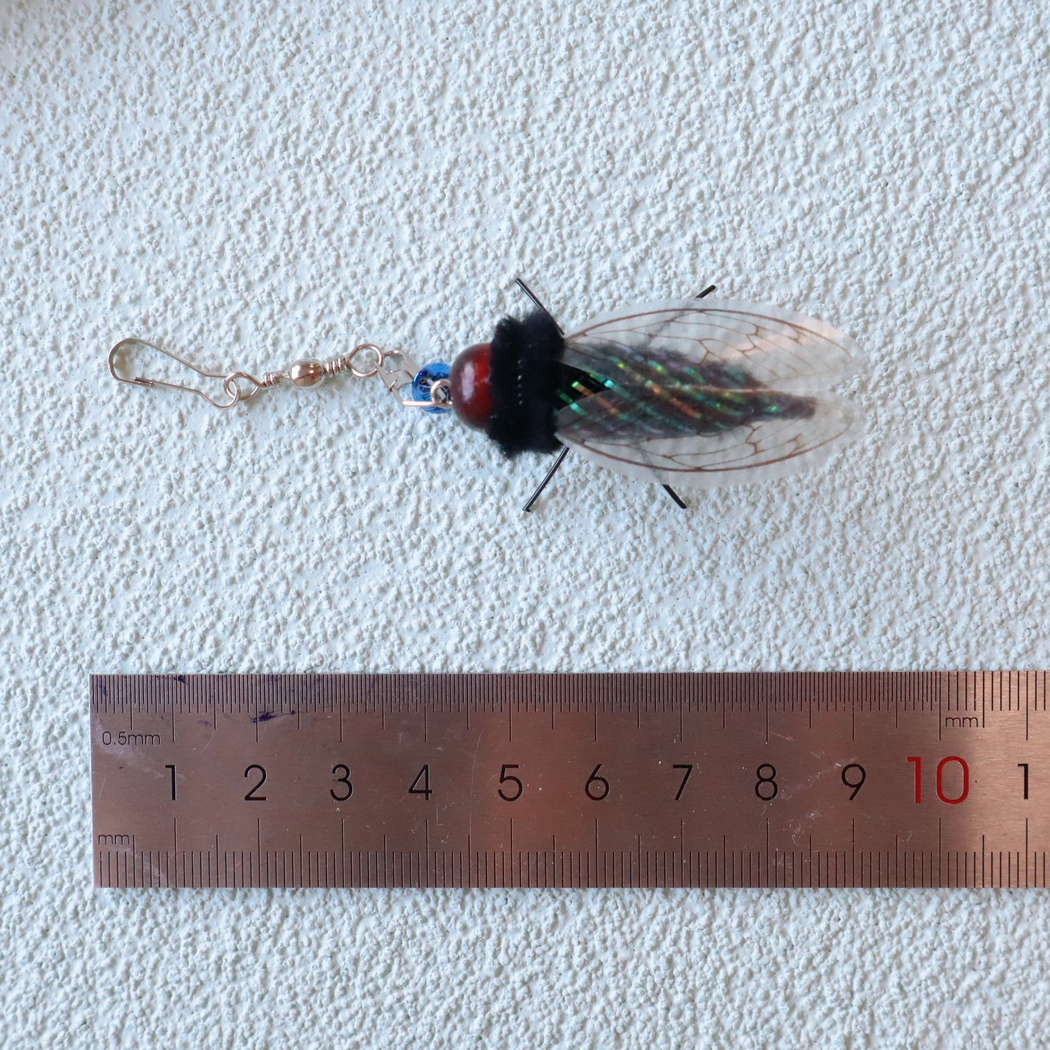 Cicada-shaped cat toy attachment beside a ruler for scale