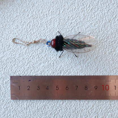 Cicada-shaped cat toy attachment beside a ruler for scale