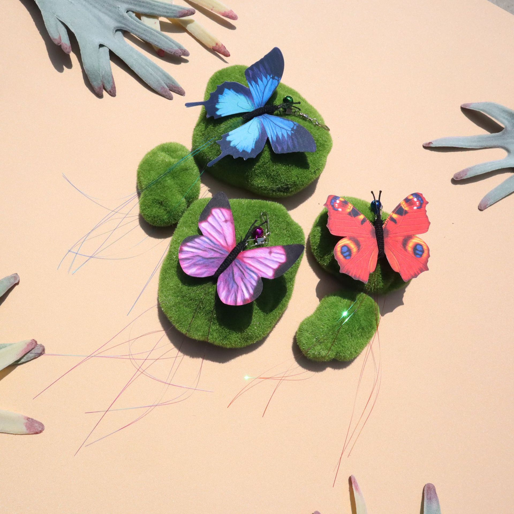 Blue, Purple and Red butterfly cat teaser replacement heads arranged on green display stones