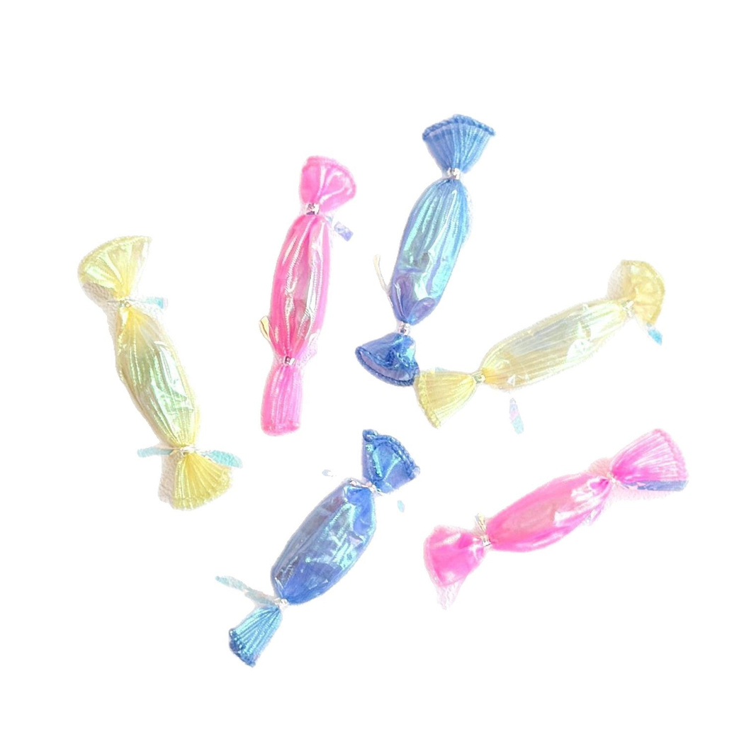 Pink, blue and yellow candy-shaped cat toys arranged on a white background