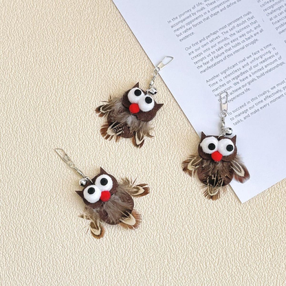 Three owl-shaped cat toy attachments arranged beside an open book