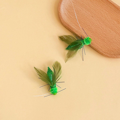 Two green winged insect-shaped cat toy attachments beside a rounded wood-look prop