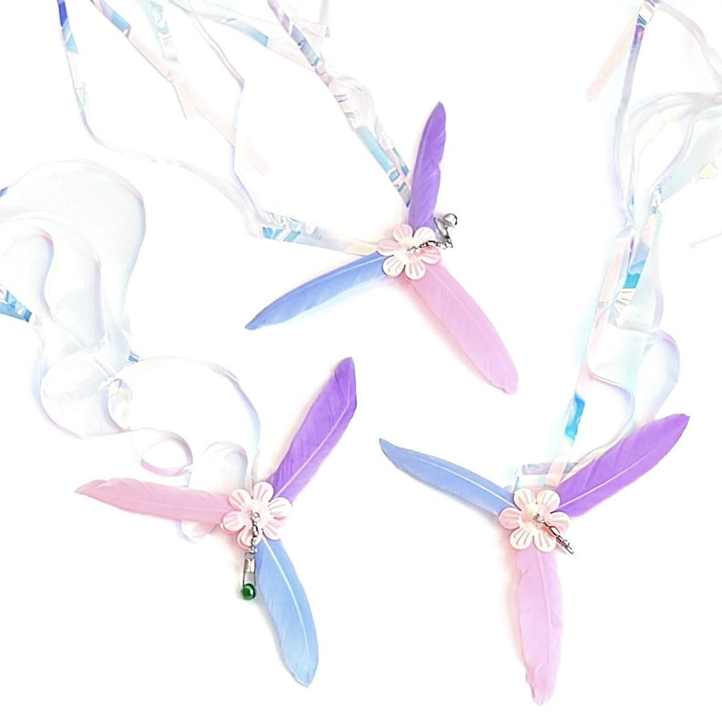 Three multicolor flower-centered cat teaser attachments arranged with curling iridescent streamers