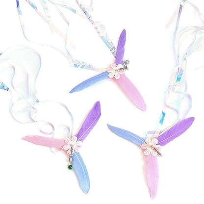 Three multicolor flower-centered cat teaser attachments arranged with curling iridescent streamers