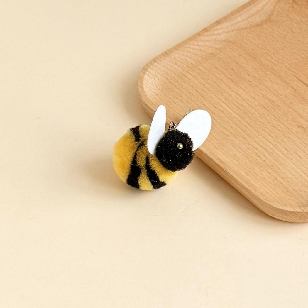 Yellow-and-black bee cat teaser attachment beside a wooden tray