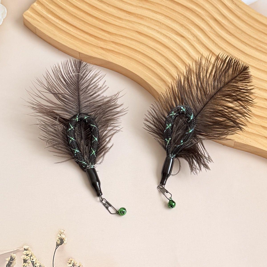 Two dark feather cat wand attachments beside a textured display board