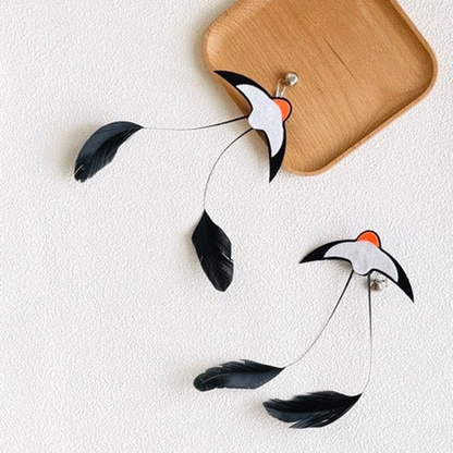 Two Swallow cat teaser attachments arranged beside a wooden tray