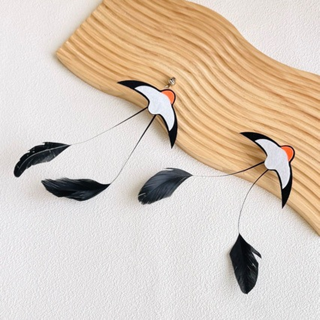 Two Swallow cat teaser attachments displayed beside a grooved wooden board