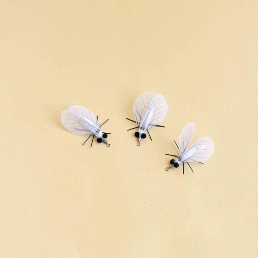 Three white moth-shaped cat toys arranged in a curved group from mixed angles