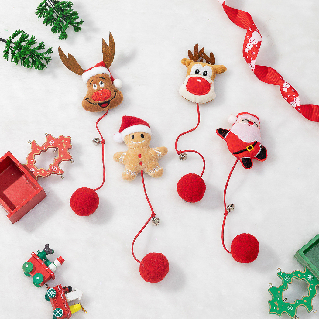 Four Christmas character pom-pom cat toys displayed with festive decorations