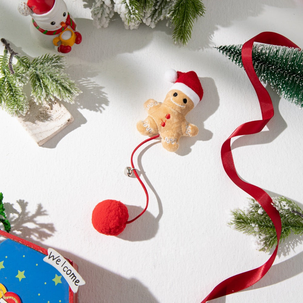 Gingerbread character pom-pom cat toy with red cord and bell