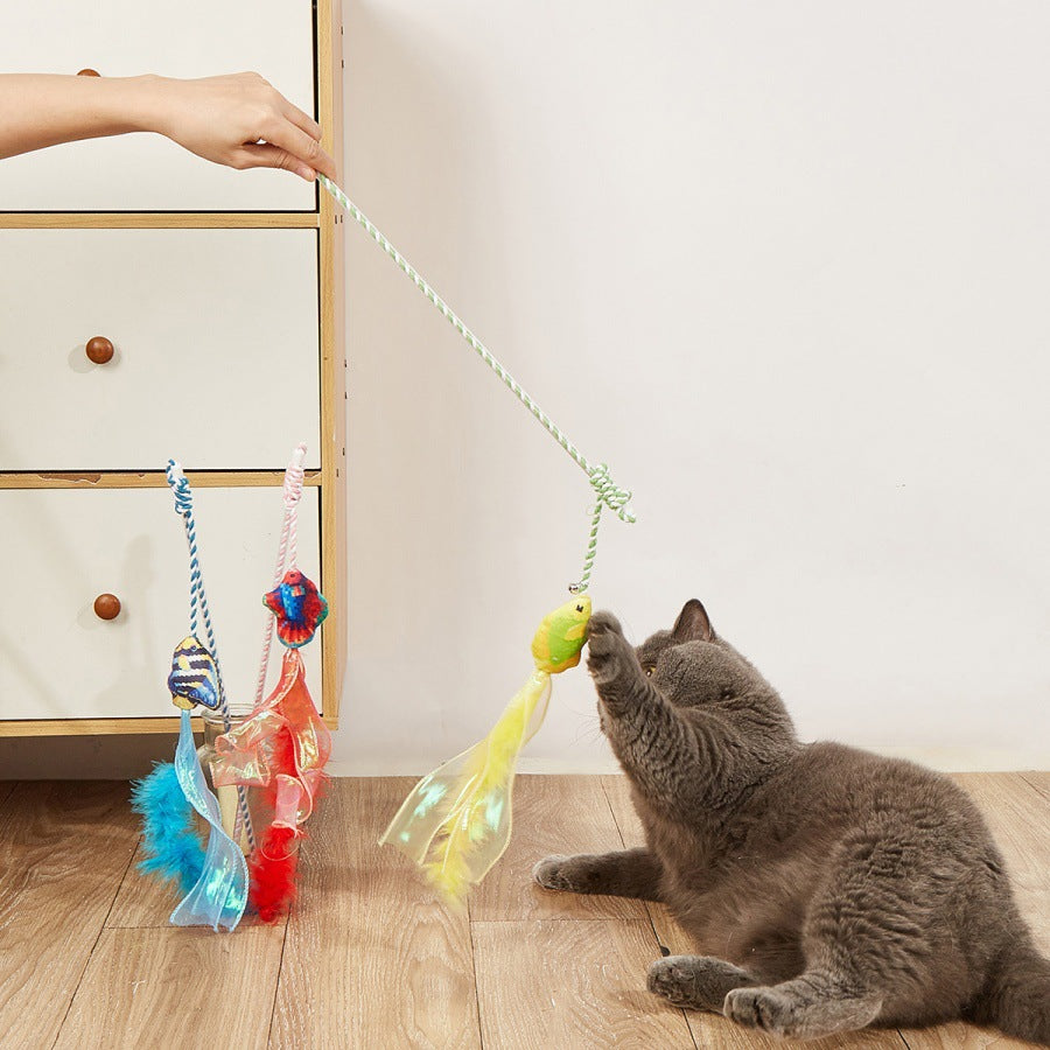 Cat playing with a yellow fish wand toy with ribbon and feather streamers