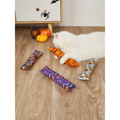 White cat holding an orange bat-print elongated cat toy in a Halloween setting