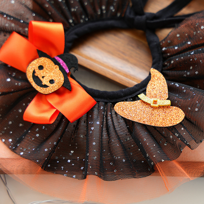 Close-up of the orange pumpkin bow, witch hat accent and speckled black ruffles