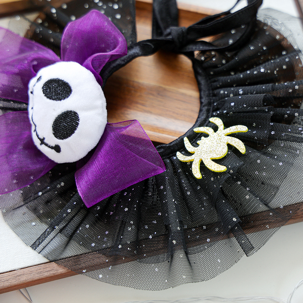 Close-up of the purple skull bow, gold-tone spider accent and speckled black ruffles