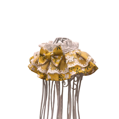 Mustard yellow floral pet neckwear with ruffled layers and bow, angled view