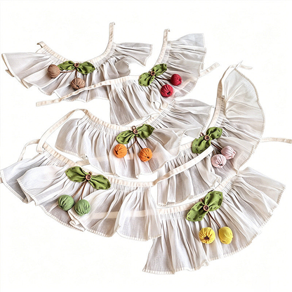 Multiple ivory pet neckwear styles with bows and cherry-shaped ornaments laid flat