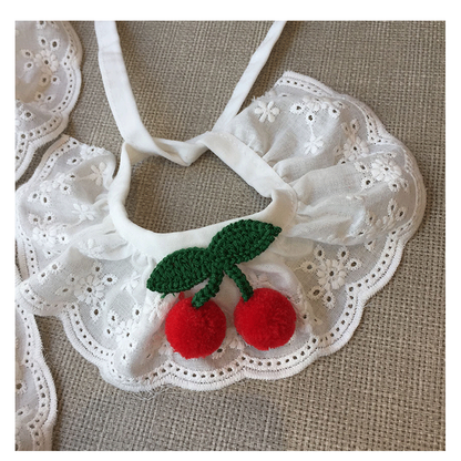 Close-up of red cherry accents, green leaves and scalloped eyelet edging