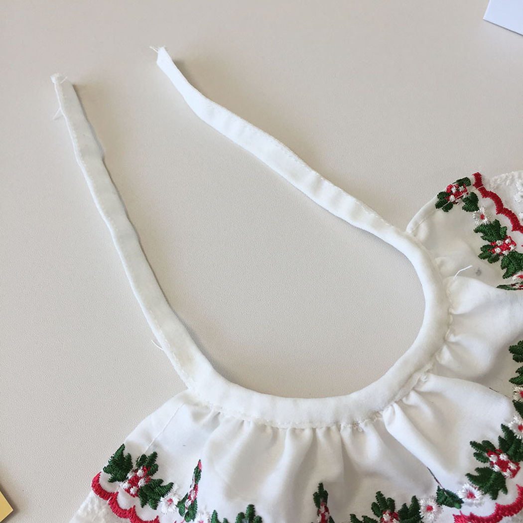 Close-up of the open neckline and two white tie straps