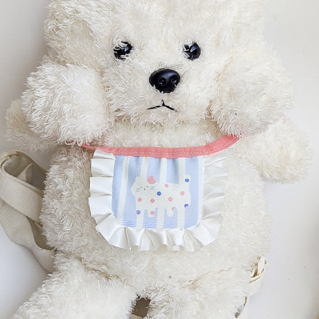 White cat-motif pet neckwear displayed on a white plush dog
