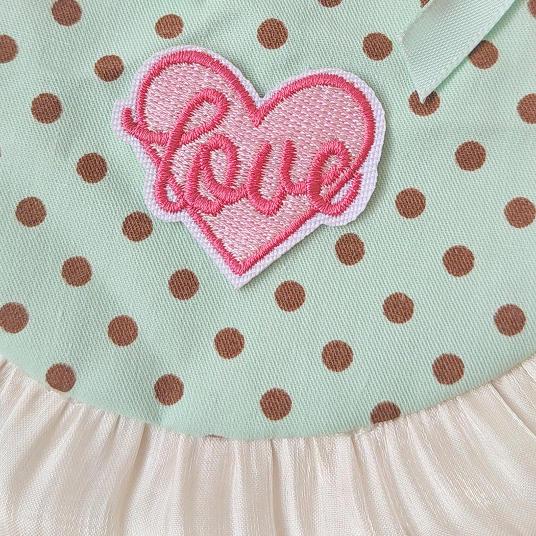 Close-up of the embroidered heart patch, mint polka dots and pleated trim