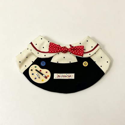 Artist-themed pet neckwear with red polka-dot bow and palette decoration, folded front view