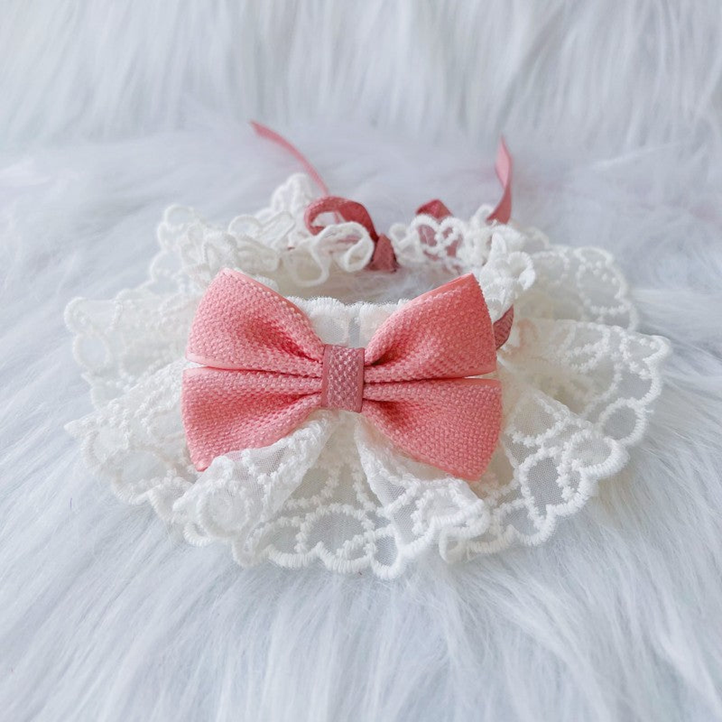 Pink pet neckwear with a centered bow and white ruffled lace-look edge