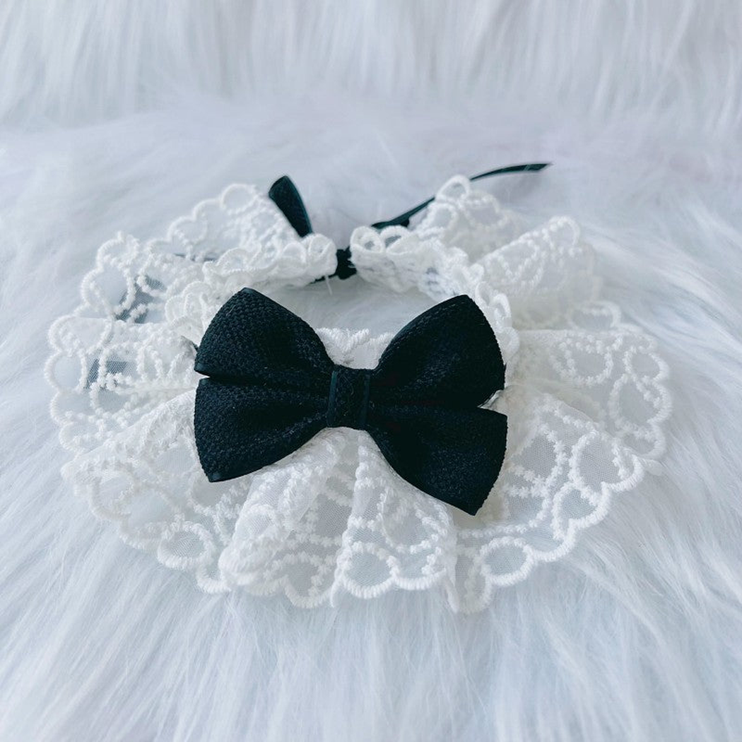 Black pet neckwear with a centered bow and white ruffled lace-look edge