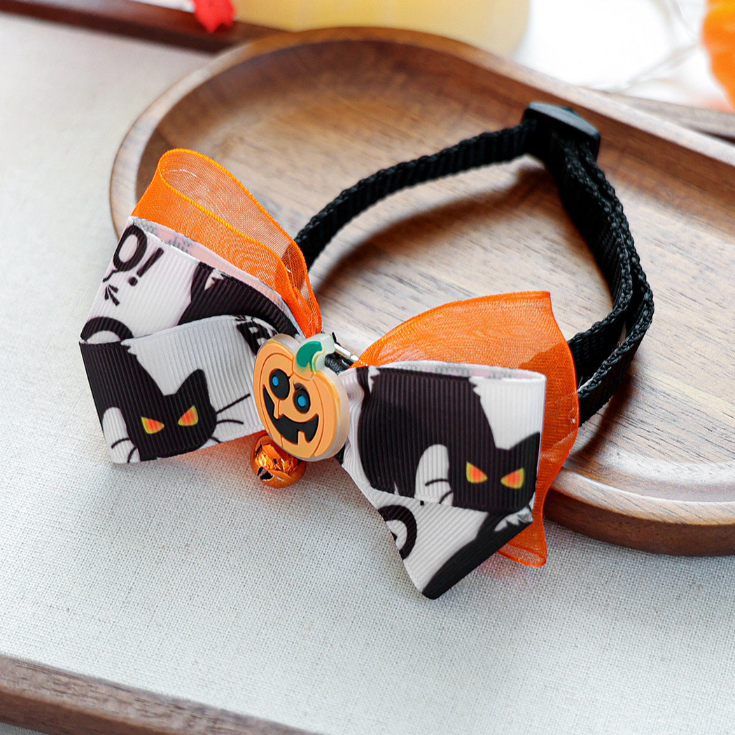 Angled view of the layered cat-print bow, pumpkin accent, bell and adjustable neck strap