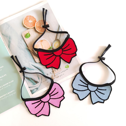 Red, light blue, and pink bow cat neckwear arranged with visible tie cords