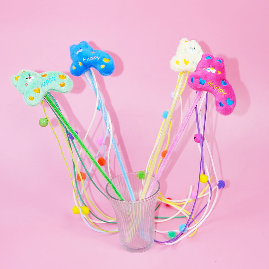 Four colorful cat teaser wands standing together against a pink background