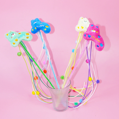 Four colorful cat teaser wands standing together against a pink background
