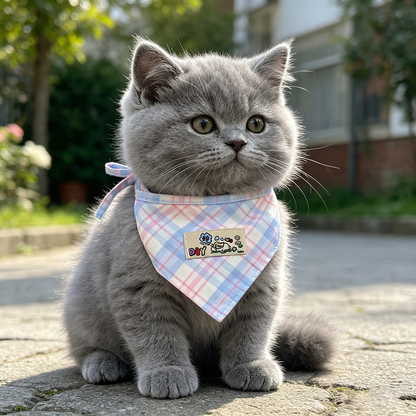 Gray cat sitting outdoors wearing Blue / Pink plaid pet neckwear with a cartoon patch.