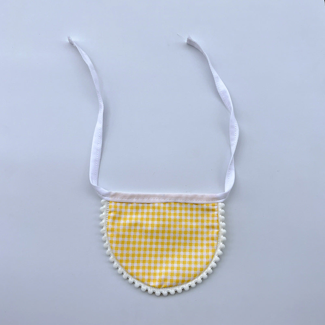 Yellow gingham Pet Neckwear with white neck ties and pom-pom edging, laid flat.