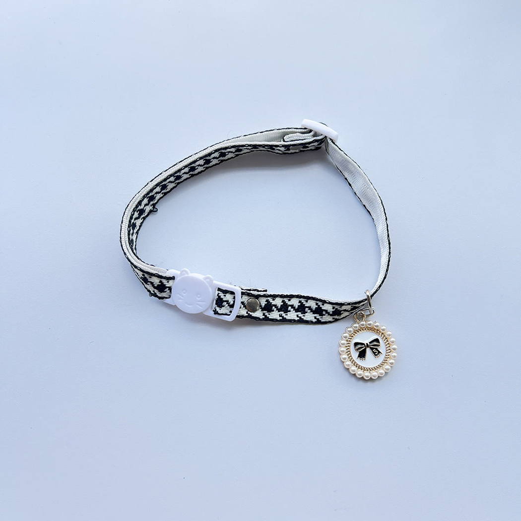 Black houndstooth cat collar with cat-face buckle and black bow charm