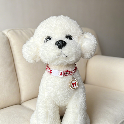 Red houndstooth cat collar with bow charm worn by a white plush dog