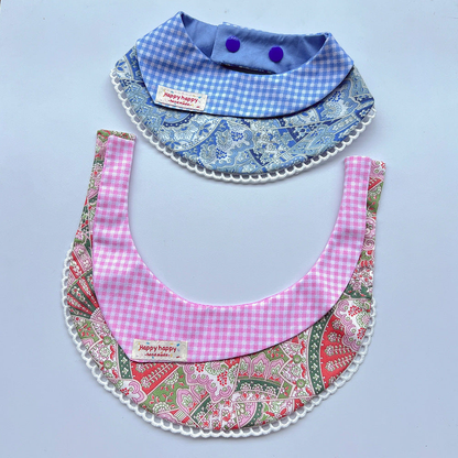 Pink pet neckwear spread open beneath a blue design, with gingham panels and white looped edges.