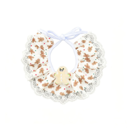 Gingerbread pet neckwear with cream patterned ruffles, a gingerbread figure decoration, white lace-look edging and ties.