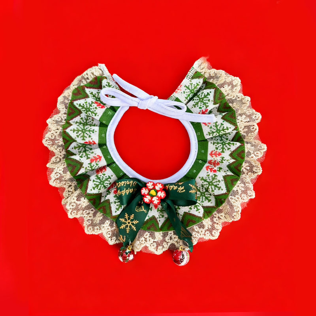 Green / Red Pet Neckwear on a red background, with snowflake-patterned ruffles, lace-look edging, tie cords, a dark green bow and dangling ornaments.