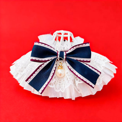 Navy bow Cat Neckwear with contrasting trim, layered white lace and a glossy pendant against a red background
